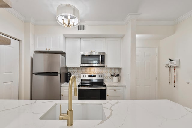 kitchen with a sink, visible vents, white cabinets, appliances with stainless steel finishes, and decorative backsplash