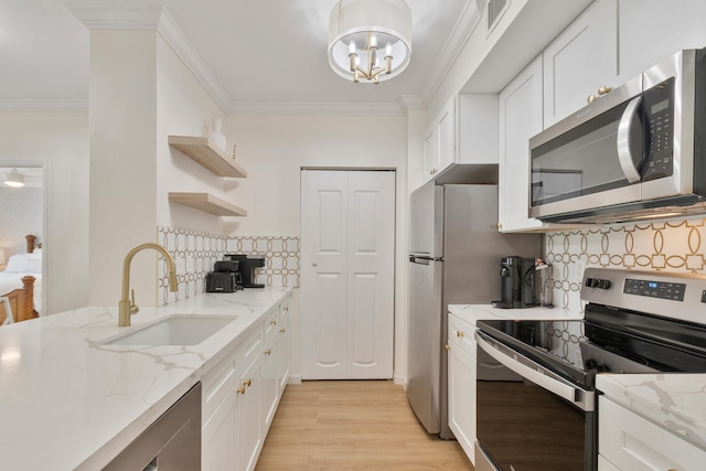 kitchen featuring white cabinetry, stainless steel appliances, a sink, and ornamental molding