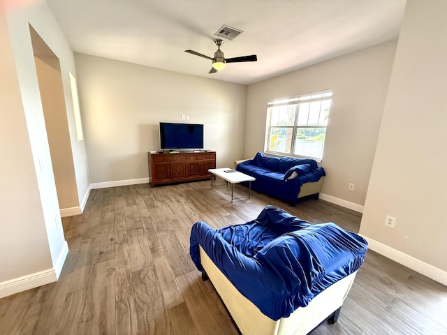 sitting room featuring a ceiling fan, wood finished floors, visible vents, and baseboards