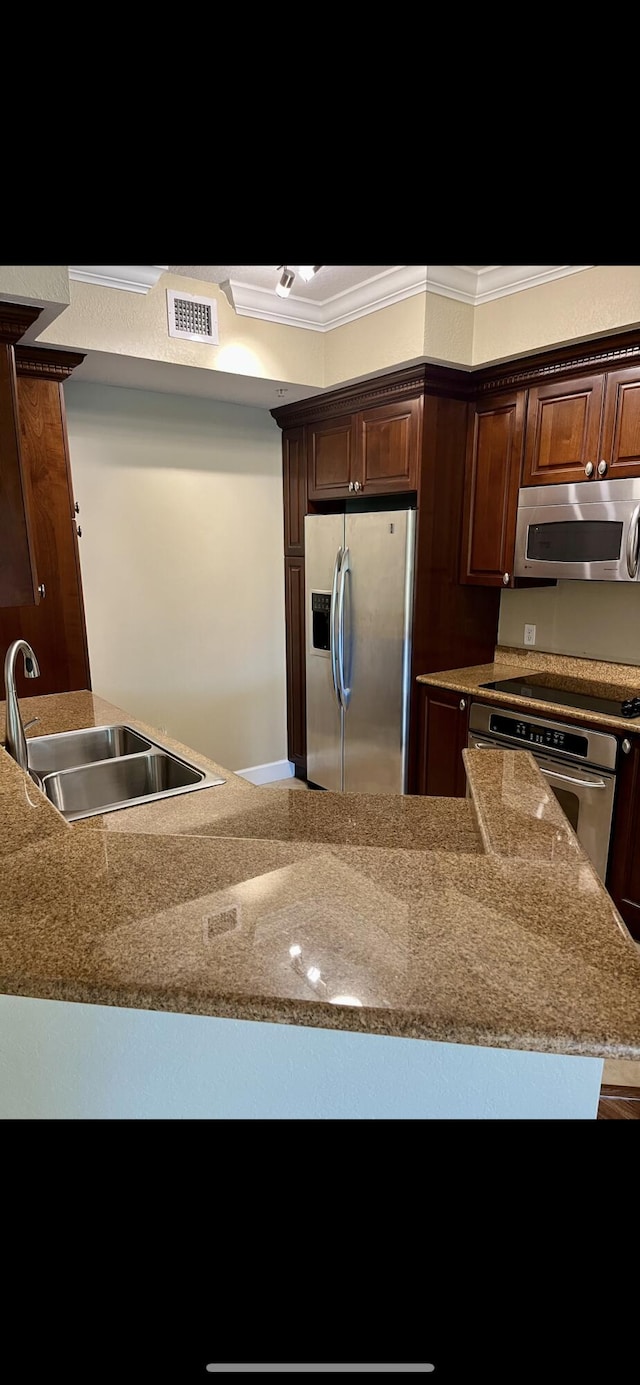 kitchen with light stone counters, crown molding, visible vents, appliances with stainless steel finishes, and a sink