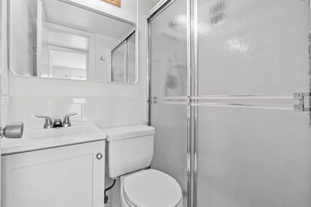 bathroom featuring toilet, a shower stall, tile walls, and vanity