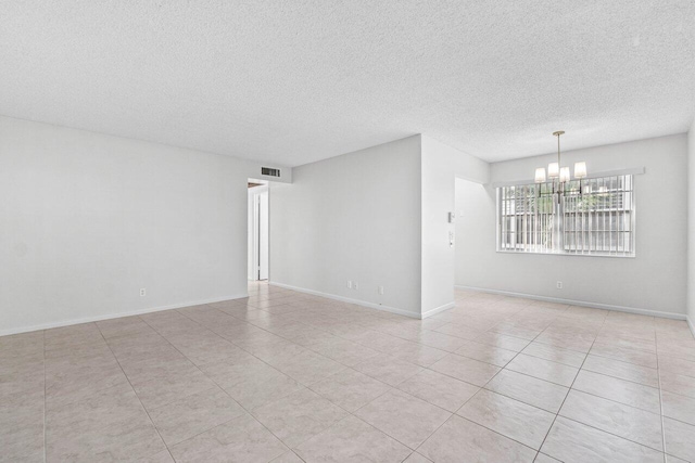 empty room featuring visible vents, a notable chandelier, a textured ceiling, and baseboards