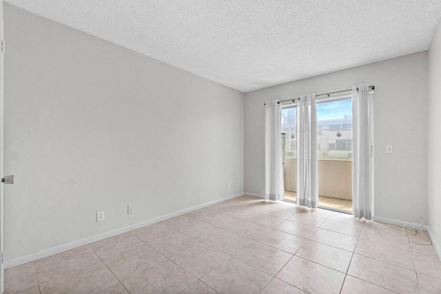 empty room with baseboards, a textured ceiling, and light tile patterned flooring