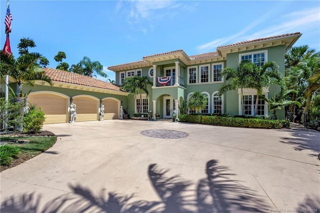 mediterranean / spanish home featuring an attached garage, a balcony, concrete driveway, french doors, and stucco siding