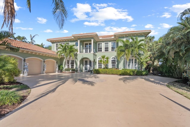 mediterranean / spanish-style house featuring french doors, stucco siding, concrete driveway, a balcony, and a garage