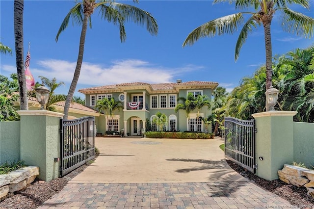 view of front of house featuring a tile roof, a gate, fence, and stucco siding