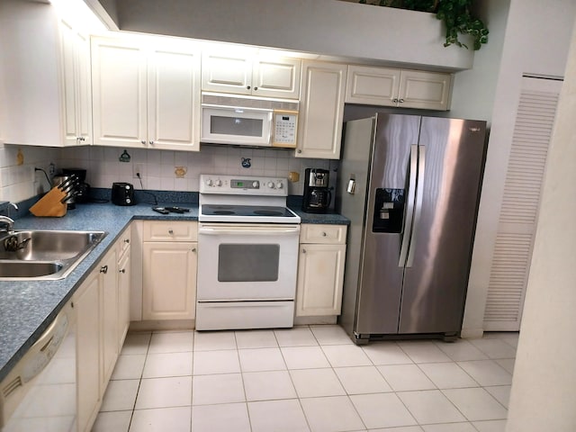 kitchen with white appliances, dark countertops, a sink, and tasteful backsplash