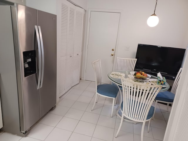 kitchen with stainless steel refrigerator with ice dispenser, decorative light fixtures, and light tile patterned flooring