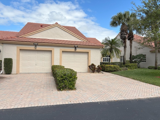 view of front of property with a tiled roof, decorative driveway, and stucco siding