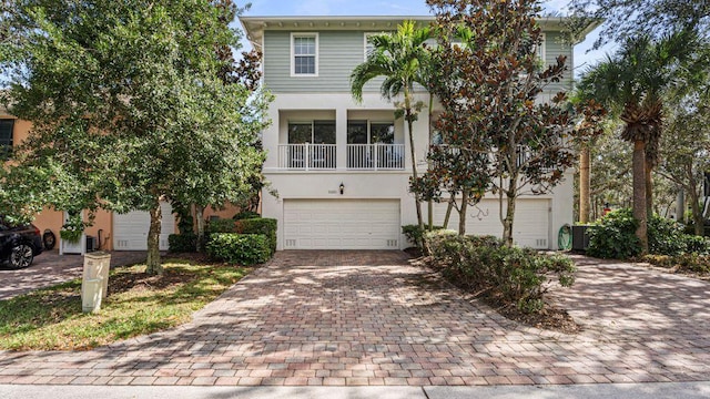 view of front of property with decorative driveway, a balcony, an attached garage, and stucco siding