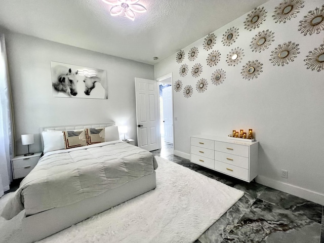 bedroom featuring marble finish floor, a textured ceiling, and baseboards