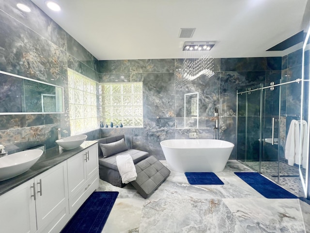 full bathroom featuring double vanity, a stall shower, visible vents, a freestanding bath, and tile walls