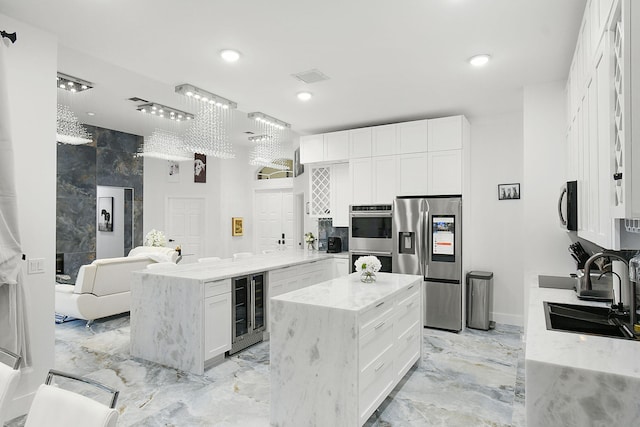 kitchen with wine cooler, a peninsula, a sink, marble finish floor, and appliances with stainless steel finishes