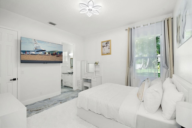 bedroom with marble finish floor, ensuite bath, visible vents, and a textured ceiling