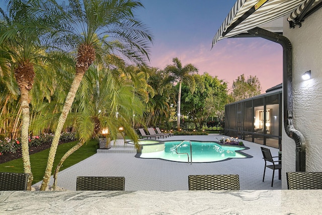 view of swimming pool featuring a pool with connected hot tub, a patio, and a sunroom