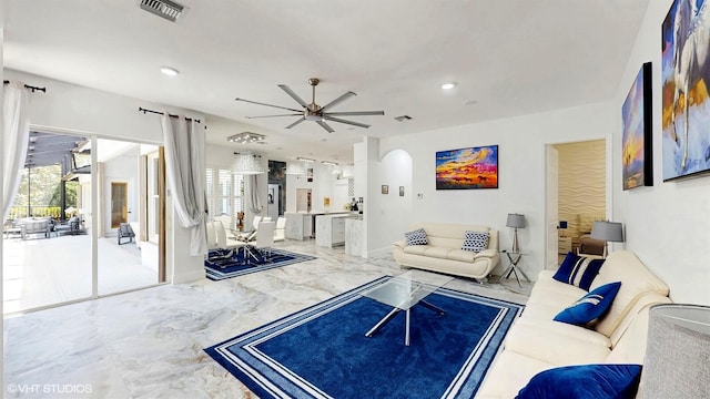 living room with marble finish floor, a ceiling fan, visible vents, and a wealth of natural light