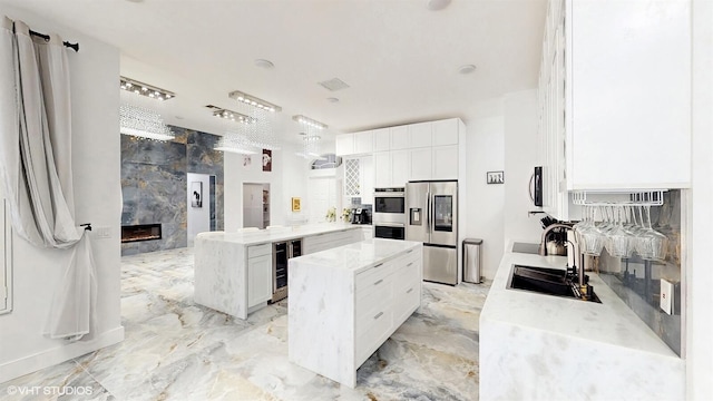 kitchen with a sink, a peninsula, a fireplace, stainless steel appliances, and beverage cooler