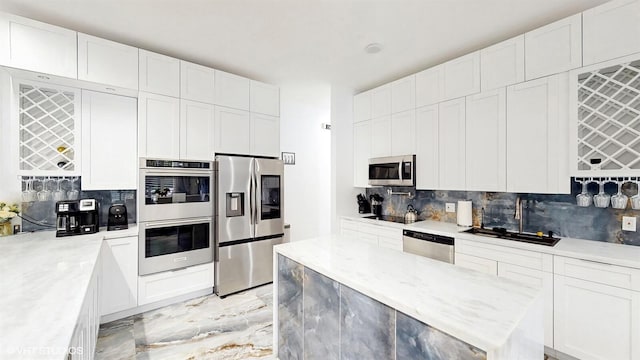 kitchen featuring stainless steel appliances, a kitchen island, white cabinetry, and decorative backsplash