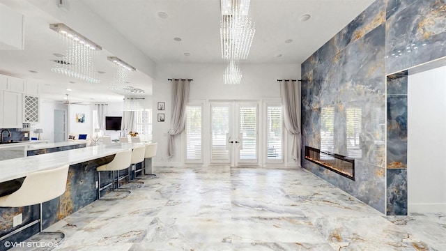 interior space with ceiling fan, french doors, marble finish floor, and a fireplace