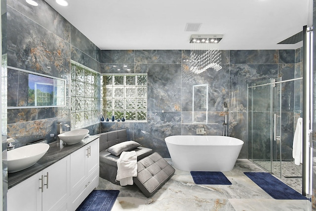 bathroom featuring a stall shower, tile walls, a sink, and a soaking tub