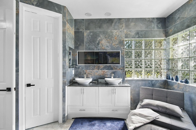 full bathroom featuring a sink, tile walls, and double vanity