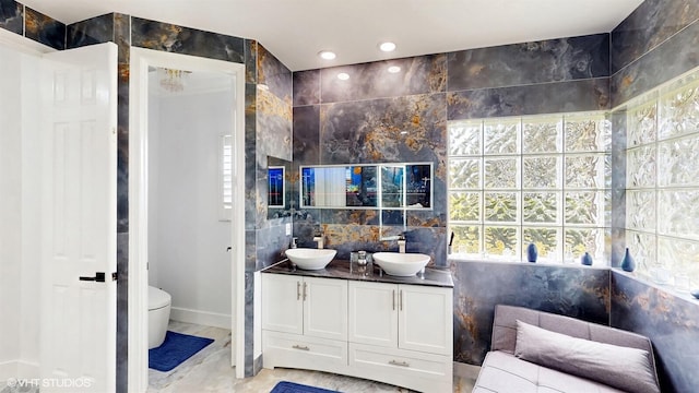 full bathroom with a sink, marble finish floor, double vanity, and toilet