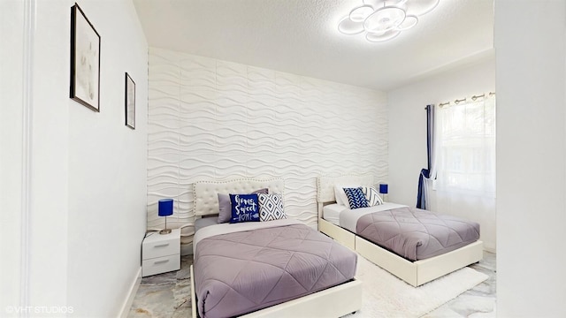 bedroom featuring baseboards, marble finish floor, and a textured ceiling