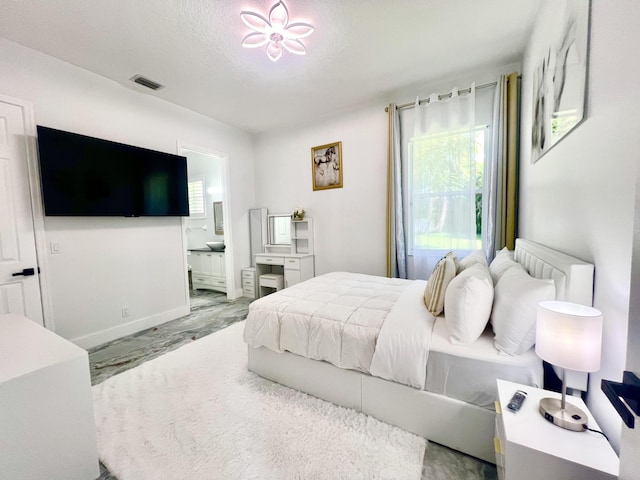 bedroom with visible vents, ensuite bathroom, and a textured ceiling