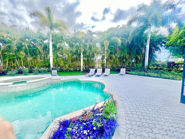 view of swimming pool featuring a pool with connected hot tub, a patio area, and fence