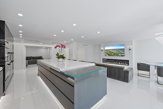 3140 S Ocean Blvd S Unit 502S, Palm Beach, FL 33480 - kitchen with modern cabinets, a spacious island, open floor plan, a glass covered fireplace, and recessed lighting