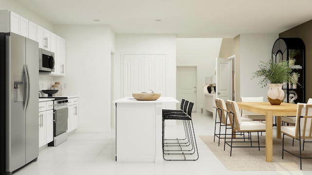 kitchen featuring white cabinets, a kitchen island, appliances with stainless steel finishes, a breakfast bar, and light countertops