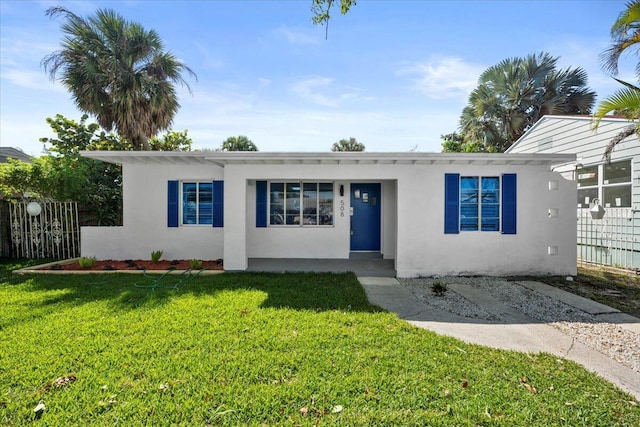 view of front facade featuring fence, a front lawn, and stucco siding