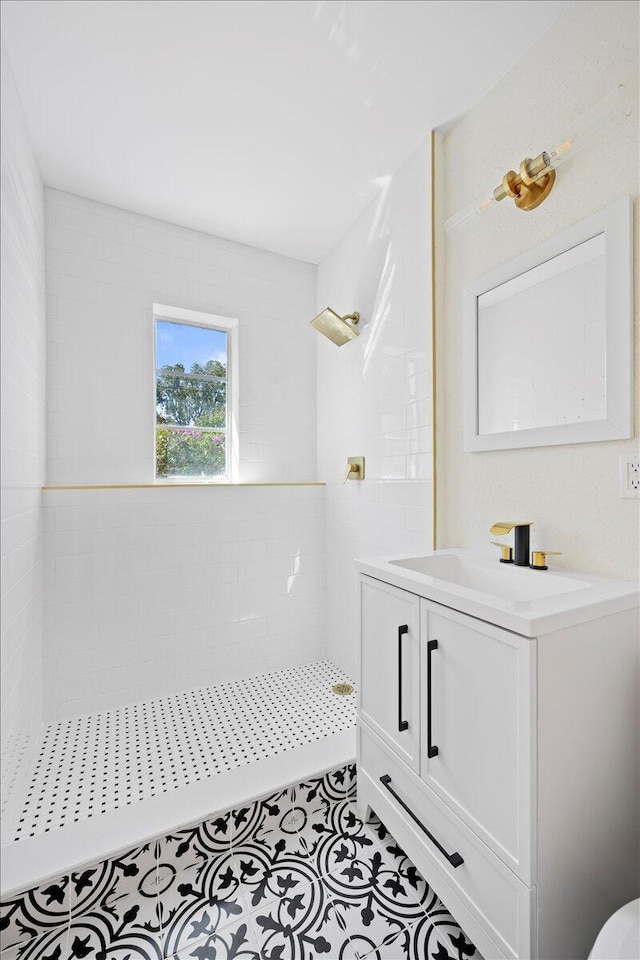 full bathroom featuring tile patterned flooring, tiled shower, and vanity