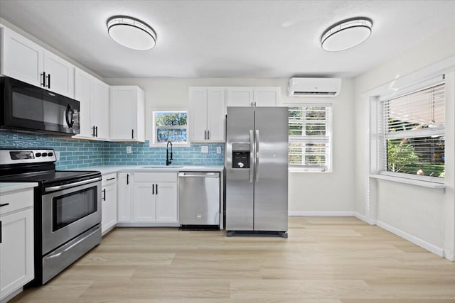 kitchen featuring an AC wall unit, appliances with stainless steel finishes, a sink, and light countertops