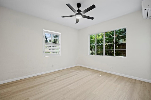 spare room with a wall mounted air conditioner, plenty of natural light, baseboards, and wood finished floors