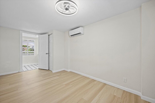 spare room with a wall mounted air conditioner, wood finished floors, and baseboards