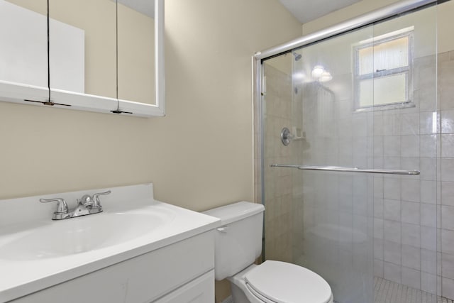 bathroom with a stall shower, vanity, and toilet