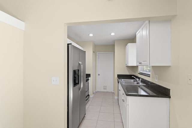 kitchen with dark countertops, white cabinetry, appliances with stainless steel finishes, and a sink