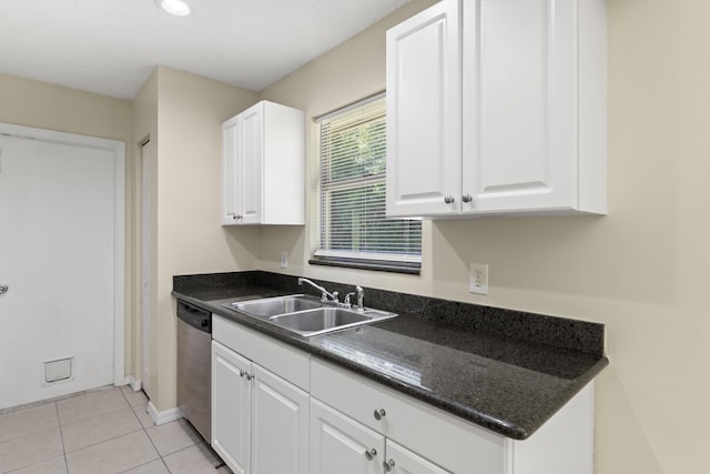 kitchen featuring dark countertops, dishwasher, white cabinets, and a sink