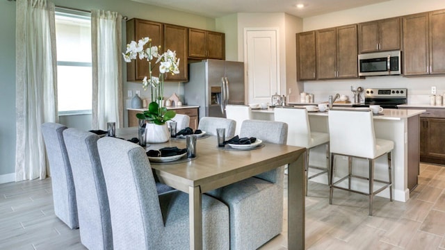 kitchen featuring stainless steel appliances, light countertops, wood tiled floor, a kitchen island, and baseboards