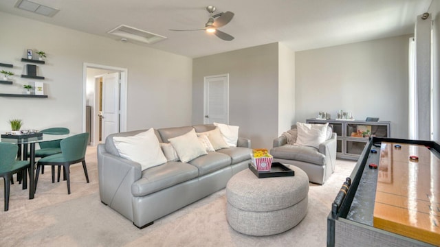 living area featuring light carpet, attic access, visible vents, and ceiling fan