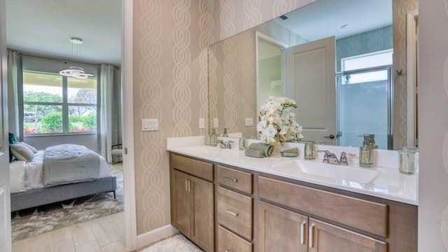 bathroom featuring a healthy amount of sunlight, wallpapered walls, ensuite bath, and a sink