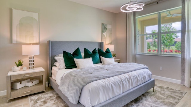 bedroom featuring a notable chandelier, wood finished floors, and baseboards