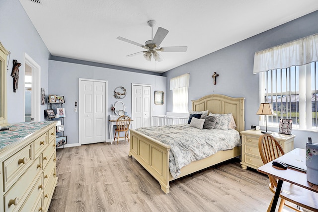 bedroom with baseboards, a ceiling fan, light wood-style flooring, and multiple closets