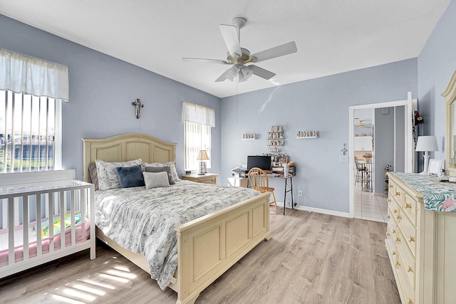 bedroom with ceiling fan, light wood-style flooring, and baseboards