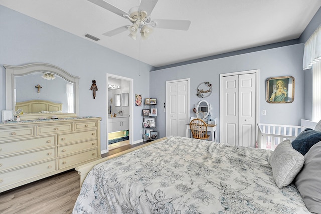 bedroom with ceiling fan, connected bathroom, visible vents, light wood-style floors, and multiple closets