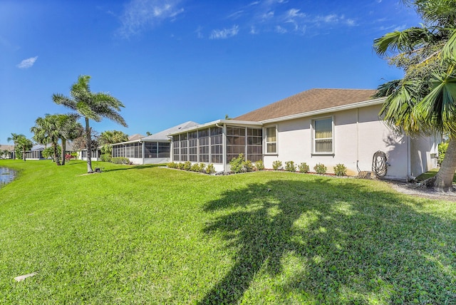 back of property featuring a lawn, a sunroom, and stucco siding