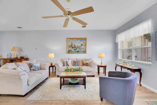 living area with a ceiling fan, visible vents, light wood-style flooring, and baseboards