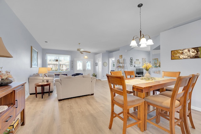 dining area featuring ceiling fan with notable chandelier, light wood-type flooring, visible vents, and baseboards