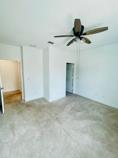 spare room featuring light colored carpet, visible vents, and baseboards